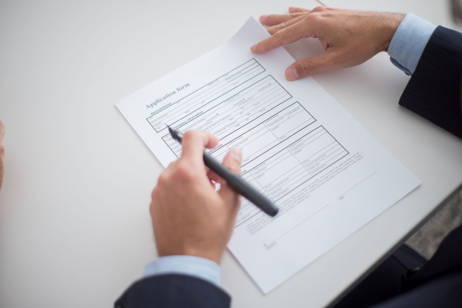 Personne remplissant un document papier au stylo