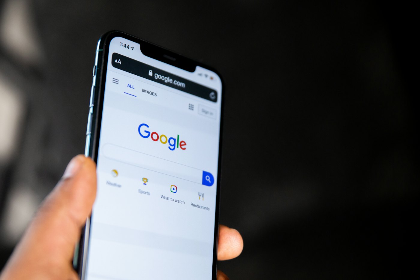 Référencement Google : une main tient un smartphone affichant la page d’accueil du moteur de recherche Google