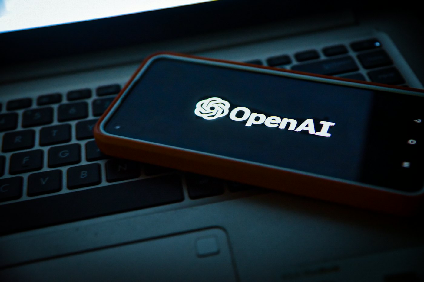 Référencement IA : un smartphone affichant le logo OpenAI posé sur un ordinateur portable